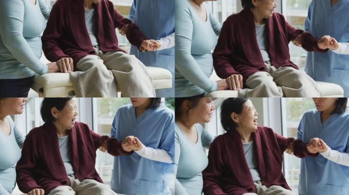 亚洲女性理疗师治疗老年女性患者的手臂，并在手术中与成年女儿