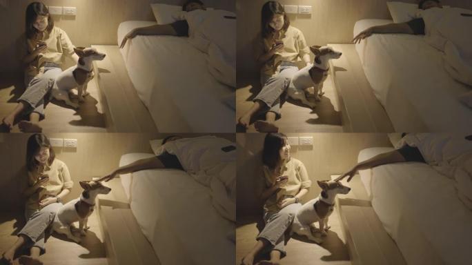躺在床上的人伸出手去玩耍和抚摸他的狗