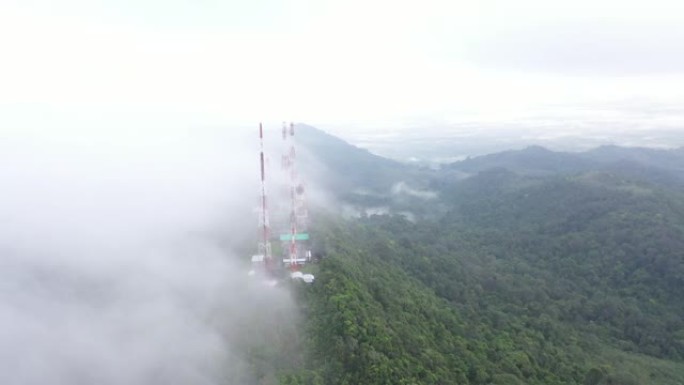 飞行无人机的鸟瞰图，具有4g和5g电信塔通信基站和天线的视差运动，在山顶上，禁食的云雾笼罩着泰国的绿