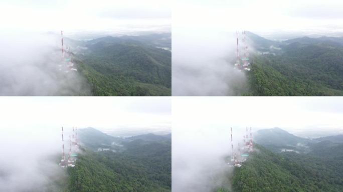 飞行无人机的鸟瞰图，具有4g和5g电信塔通信基站和天线的视差运动，在山顶上，禁食的云雾笼罩着泰国的绿