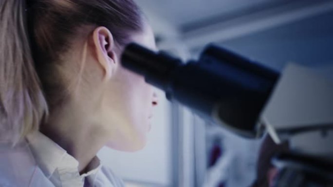 研究期间的女性微生物学家。在未来实验室中使用显微镜。背景研究伙伴
