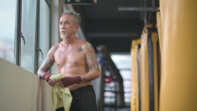 亚洲中国高级泰拳运动员在健身房锻炼后用毛巾擦拭身体