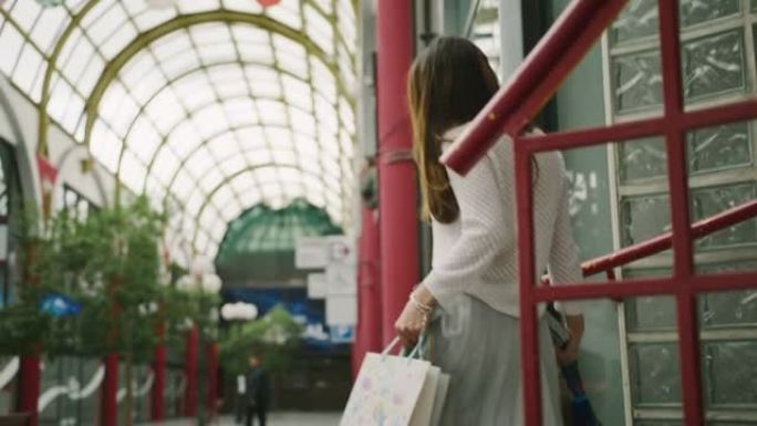 年轻女子在购物中心散步时拿着购物袋