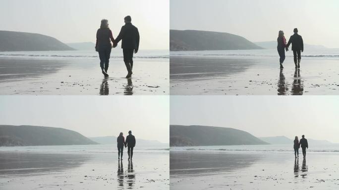 老年夫妇在海滩上慢动作行走的后视图