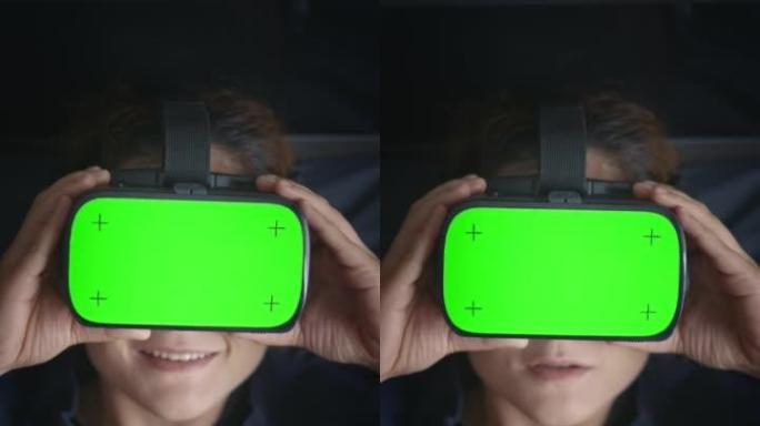 垂直拍摄女子戴彩色键绿屏VR耳机趴在床上