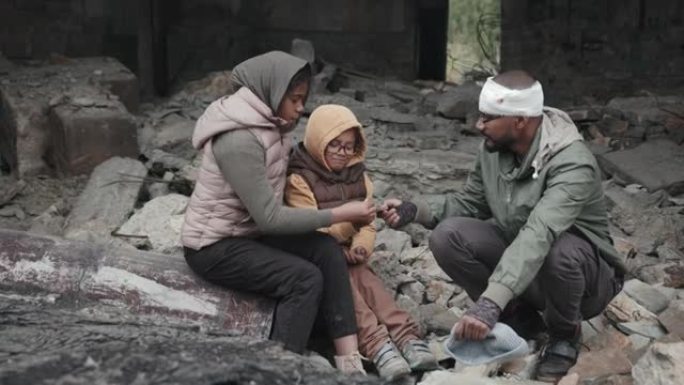 坐在被拆毁房屋废墟中的难民