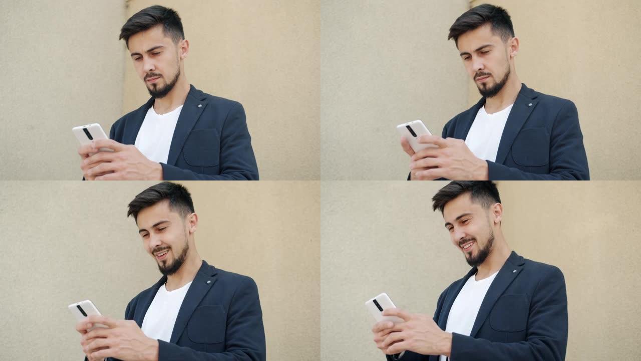 成功的混血商人使用智能手机发短信微笑着看着户外的屏幕