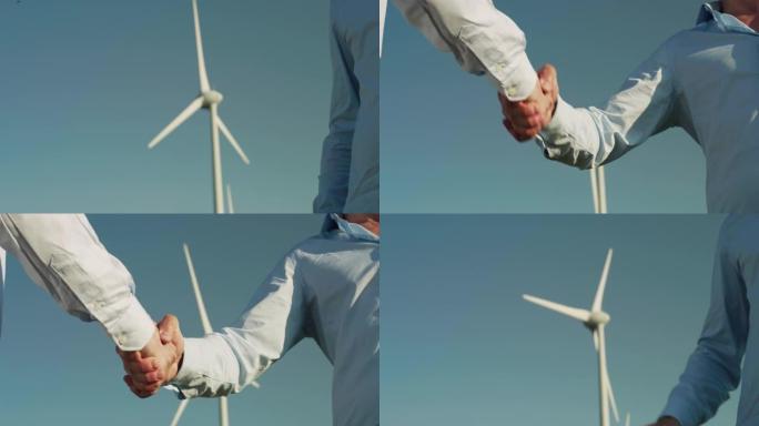 在达成有关建设风电场的协议后，两名男性成年人握手。工程师同意为子孙后代建立更好的生态环境