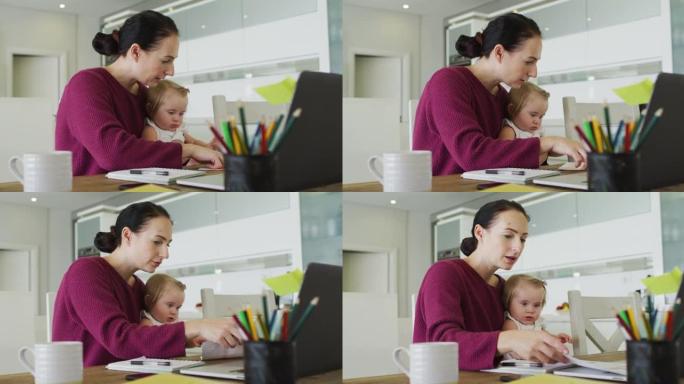 白人母亲在家工作时用笔记本电脑抱着婴儿