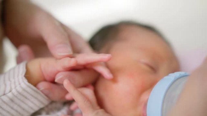 单身母亲牵着他的手给刚出生的男婴喂山羊奶粉。无乳糖配方
