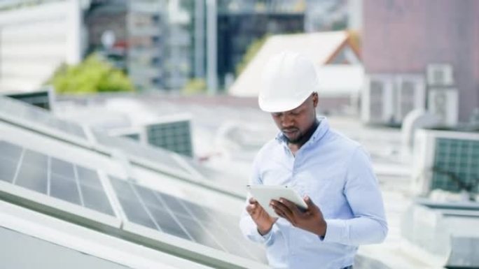 一个年轻人在建筑物的屋顶上安装太阳能电池板时使用数字平板电脑。一名男子在网上从事可再生能源建筑项目