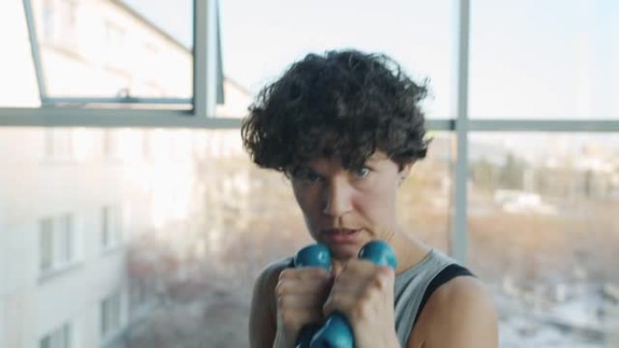 年轻女运动员独自在健身房锻炼的哑铃挥拳的肖像