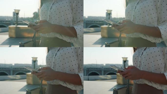 夏日现代城市户外女性双手触摸智能手机屏幕的特写