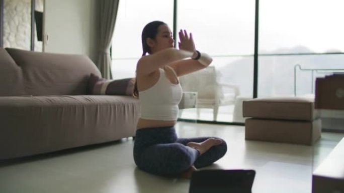 女人在笔记本电脑上看瑜伽课，在家做运动