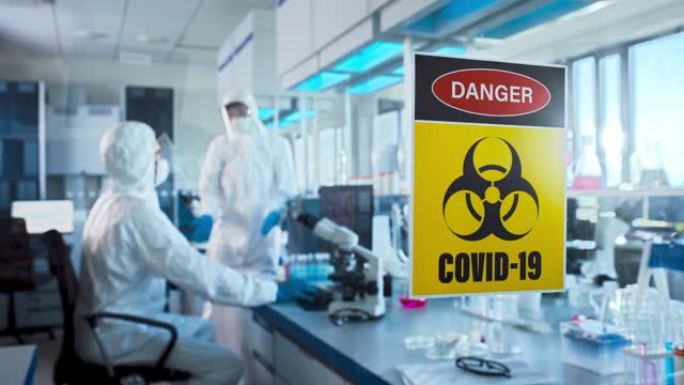 医学研究实验室门上的危险新型冠状病毒肺炎标志: 戴着口罩的科学家团队致力于新型冠状病毒肺炎治疗，疫苗