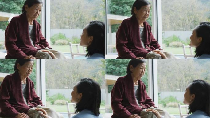 微笑的亚洲女性理疗师治疗高级女性患者的膝盖并在手术中交谈