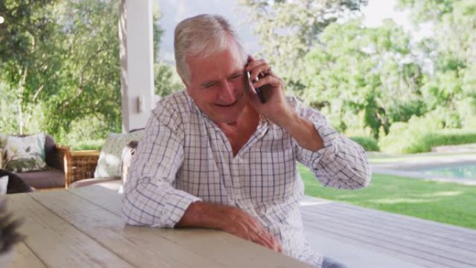 白人老人在花园里微笑着在电话里聊天