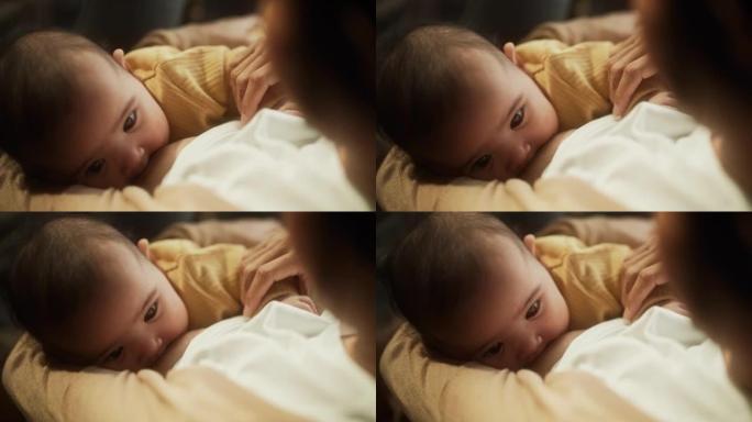 一个可爱的亚洲婴儿从母亲的乳房喂养的高角度肖像。新母亲和婴儿之间的亲密时刻表现出母爱，温柔和无条件的
