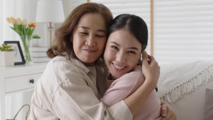 亚洲家庭母女在家里沙发上拥抱拥抱。