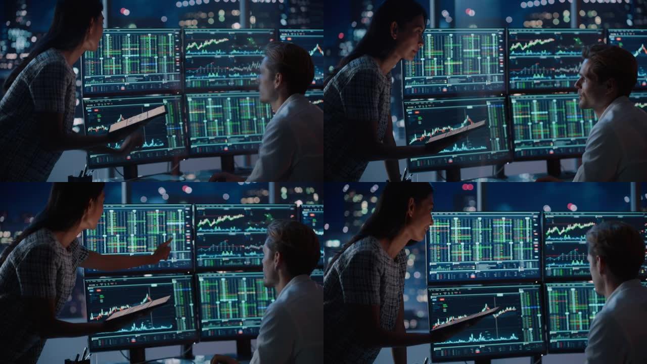 财务分析师晚上在工作中与投资银行家交谈。在多显示器工作站上聊天实时股票图表数据。商人在经纪人代理办公
