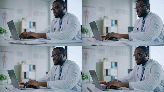快乐的非洲裔美国家庭医生正在一家健康诊所的笔记本电脑上工作。穿着白大褂的医生正在医院办公室的桌子后面