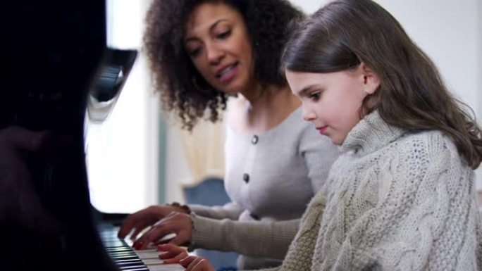 年轻女孩从女老师那里学习弹钢琴