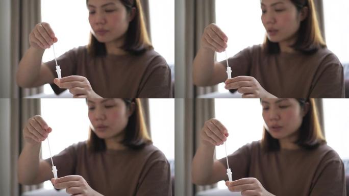 女人呆在家里，自己使用抗原测试试剂盒进行新型冠状病毒肺炎测试