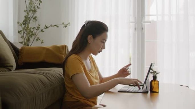 年轻的亚洲妇女用信用卡在笔记本电脑上购物