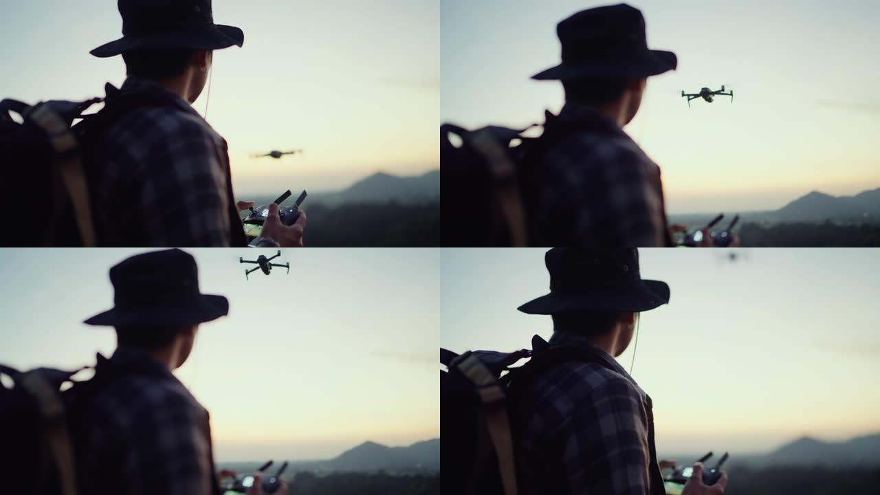 早上在山景上使用无人机的亚洲游客的剪影。