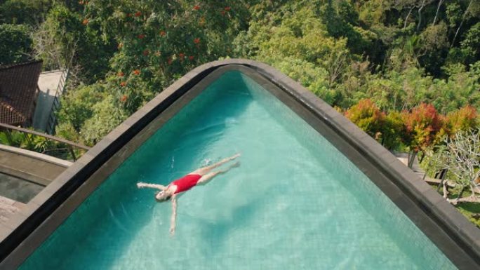 顶视图快乐的女人漂浮在热带酒店水疗中心的游泳池里，丛林享受异国情调的暑假4k放松
