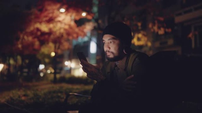 亚洲男子自由职业者晚上在城市地区看着他的智能手机。