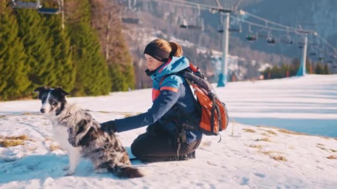 SLO MO年轻女子在滑雪缆车的视野中拥抱她的狗在斜坡上