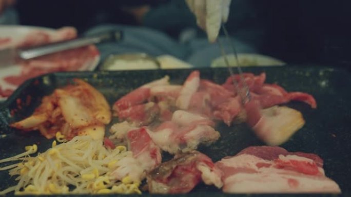 亚洲人在烤架上翻转美味的韩国烧烤的特写镜头。