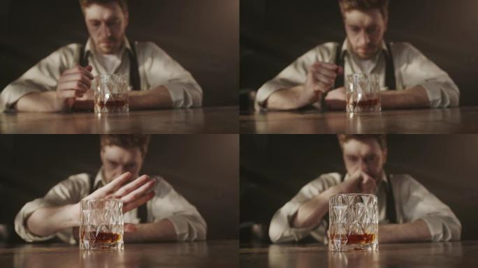 一个穿着衬衫和领带的疲倦的醉酒经理在一个黑暗的酒吧里受苦，他看着一杯威士忌，试图停止喝酒，知道自己有