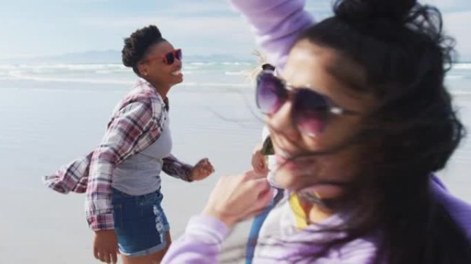 快乐的一群不同的女性朋友在海滩上玩得开心，跳舞和微笑