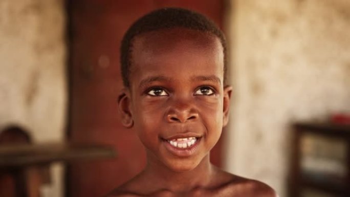 一个可爱的小非洲孩子的特写肖像，带着美丽的微笑看着相机。农村快乐男孩代表着纯真、和平与希望。纪录片镜