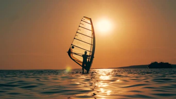 风帆冲浪者在夕阳下渡海