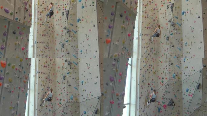 空中: 女性登山者使用自动保护装置降落在攀岩墙上