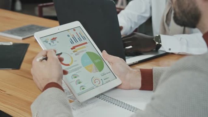 男性投资者分析平板电脑显示屏上的商业图表和图表