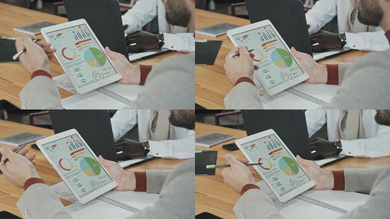 男性投资者分析平板电脑显示屏上的商业图表和图表