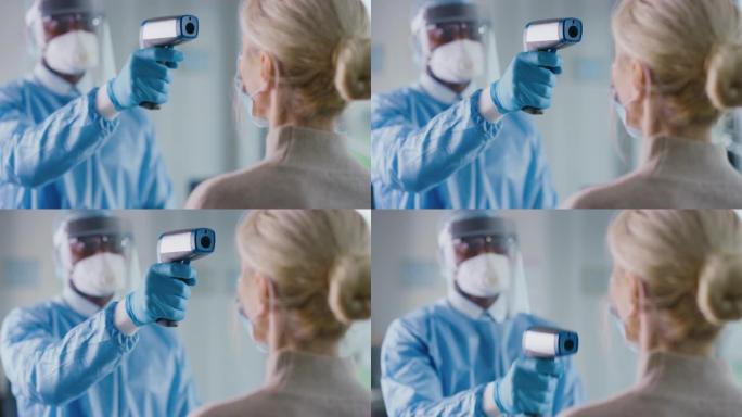 在健康诊所用红外温度计测量高级女性患者体温的安全钳医生的特写。医生使用免触摸技术来诊断症状。