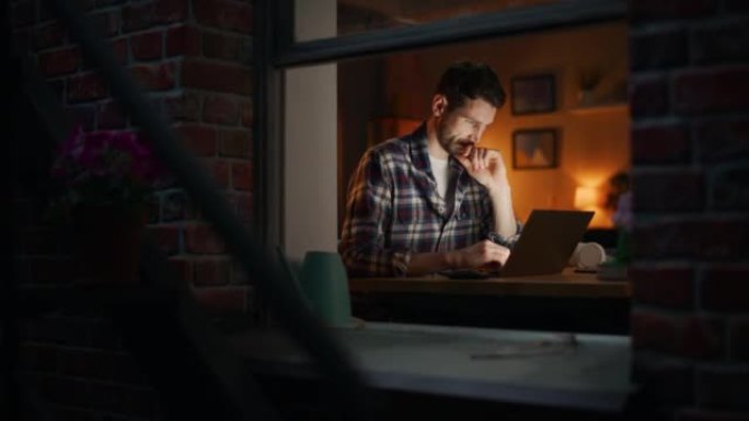 白人男子在家庭办公室远程工作时使用笔记本电脑。英俊的男性坐在桌子旁，在电脑上工作，集思广益，浏览互联