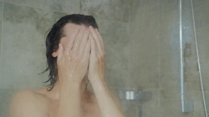 英俊的年轻长头发男子洗脸和洗澡在家里