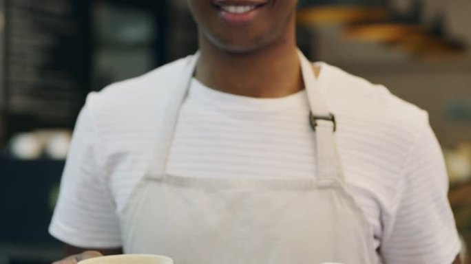 4k视频片段，一个年轻的男性面包师在面包店拿着一杯咖啡和一个盘子