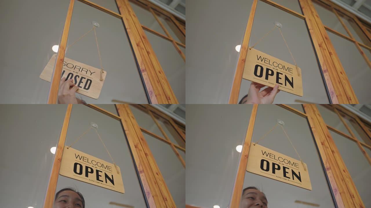 女人在商店的门上挂了一个开放的标志
