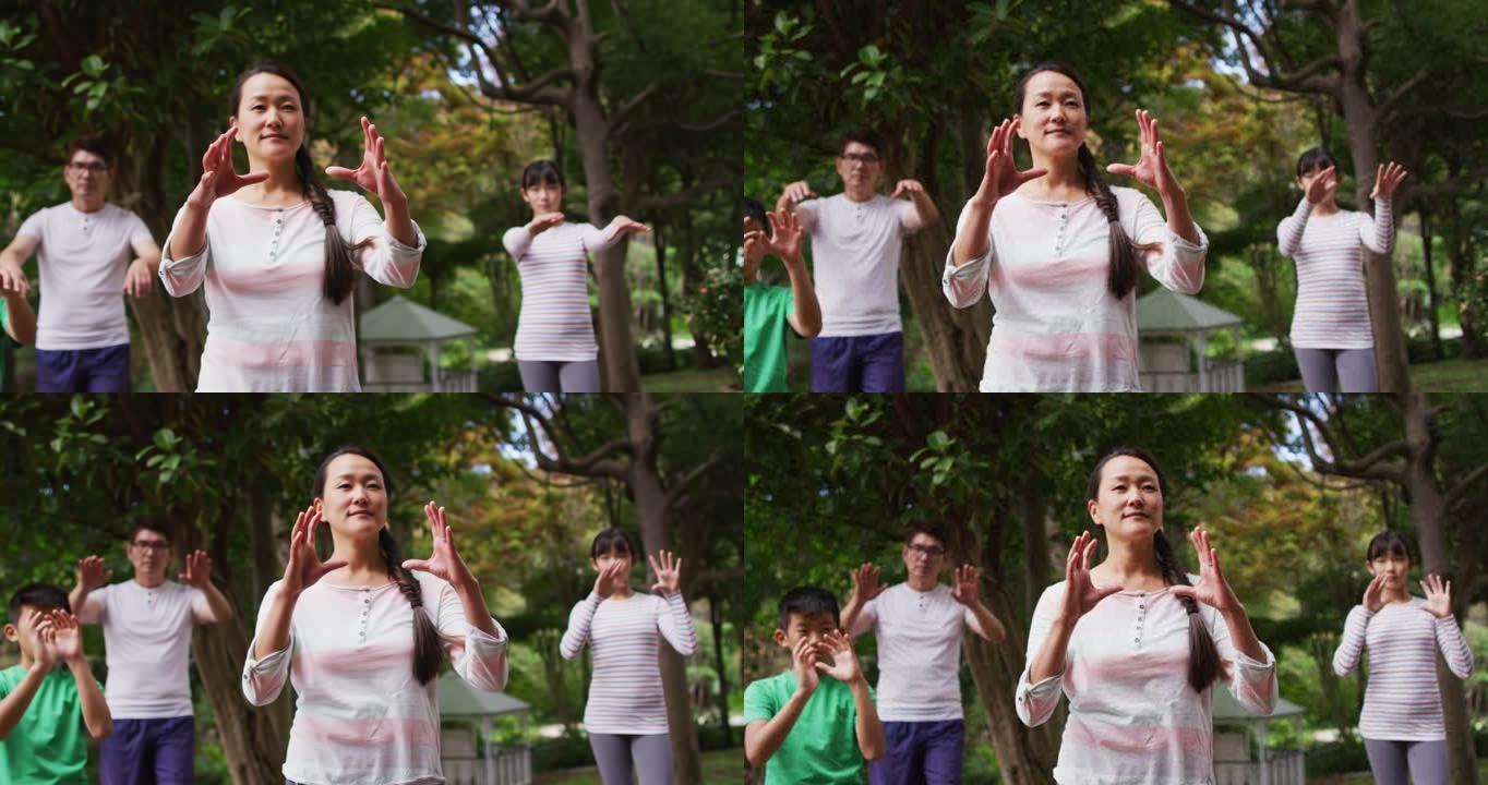 快乐的亚洲父母与儿子和女儿在花园里锻炼，一起练习太极拳