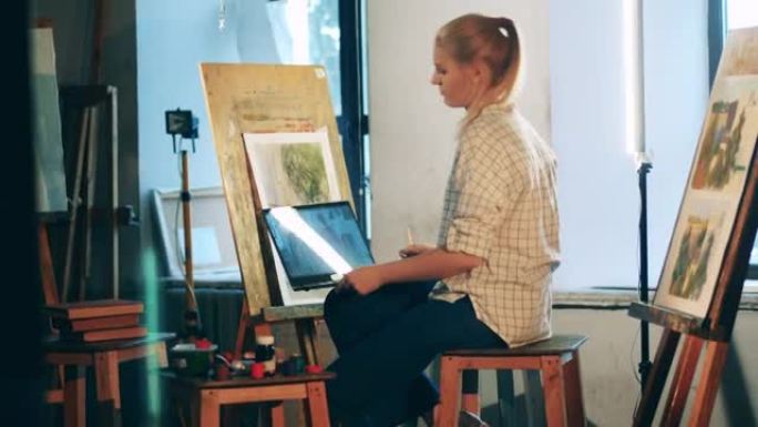 金发女人正在艺术工作室里上视频课。创意爱好，艺术品生物概念。
