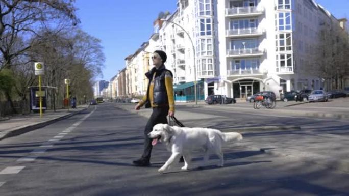 女人带着她的狗穿过城市街道
