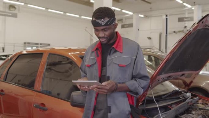 非裔美国机械师在汽车维修车库中使用平板电脑