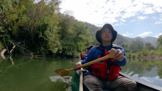 亚洲男子在河边划着独木舟